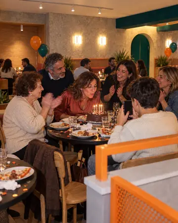Un compleanno a tavola, la torta con le candeline e la mamma che applaude.